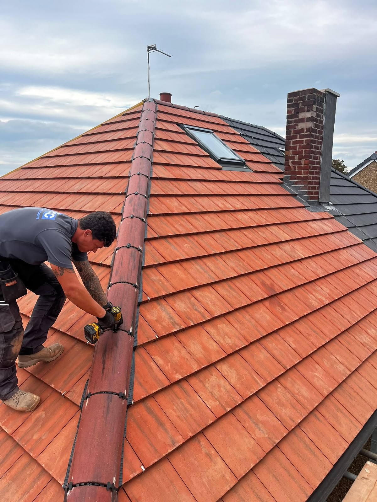 RTC roofer replacing a red clay hip tile with dry-ridge clips during a repair on a Wirral roof