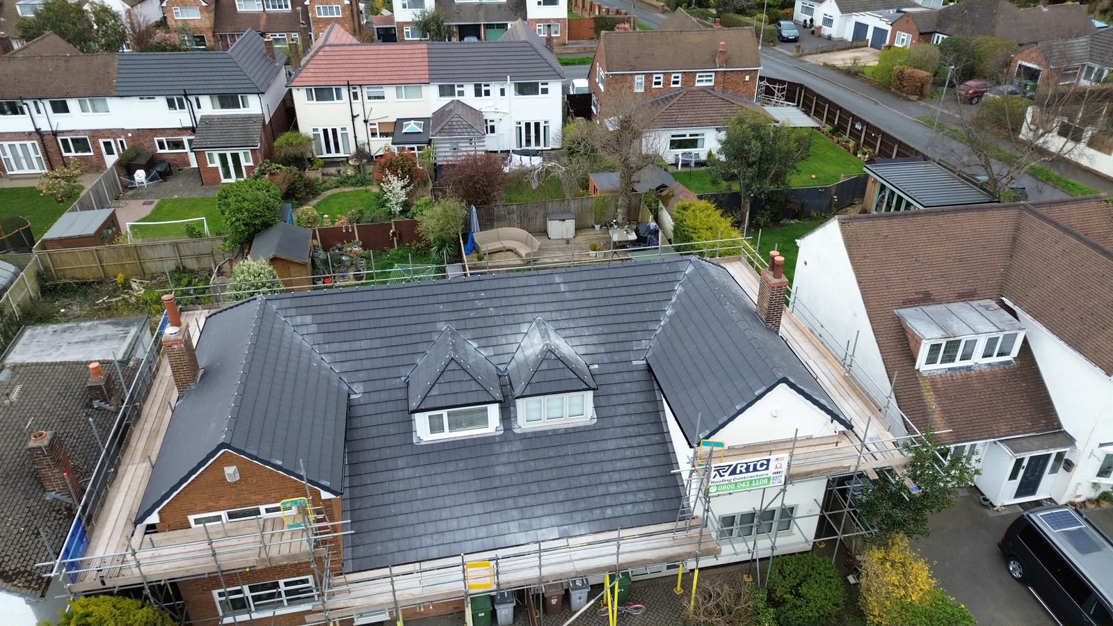 Full pitched re-roof completed by RTC Roofing on a Wirral semi-detached home with new grey concrete interlocking tiles, fresh ridge and scaffolded elevations